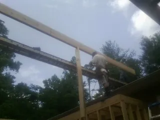 Carpenter setting a ridge beam over a new addition frame — Ice Dam Removal by Roofing Brothers in Wedgefield