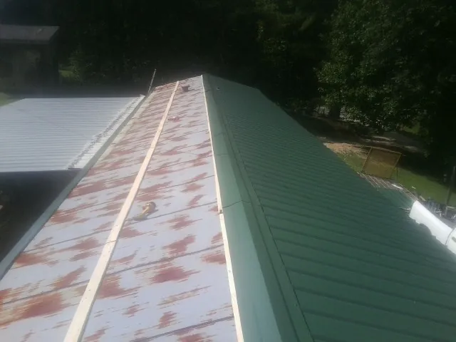 Old rusted panels beside newly installed green metal roofing — Wind Damage Roof Repair by Roofing Brothers in Wedgefield