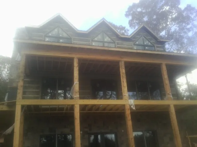 Dormers and porch framing on a large log home under construction — Roof Coating work by our crew in Wedgefield
