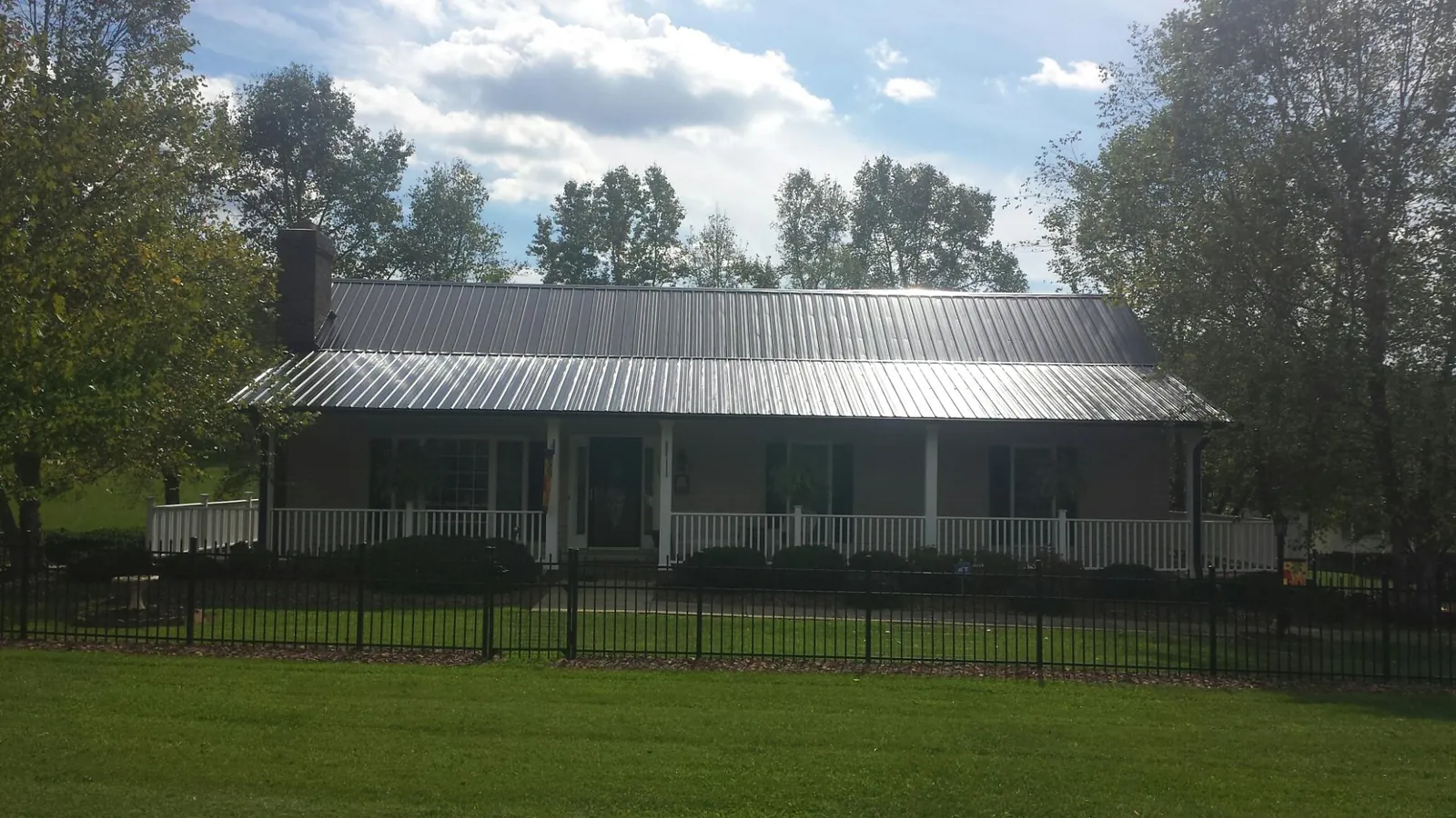 Gray metal roof on a brick ranch with a full width front porch — Gutter Guard Installation work by our crew in Wedgefield