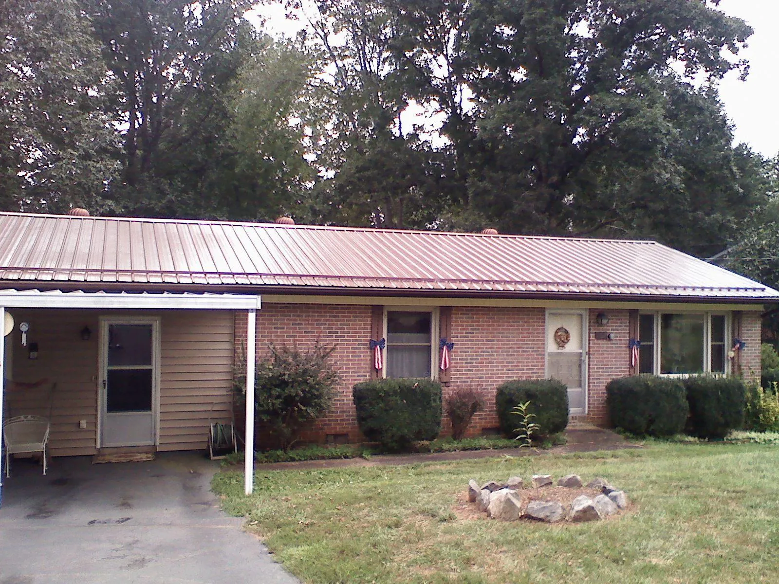 Bronze metal roof and carport on a brick ranch home — Roof Repair work by our crew in Wedgefield