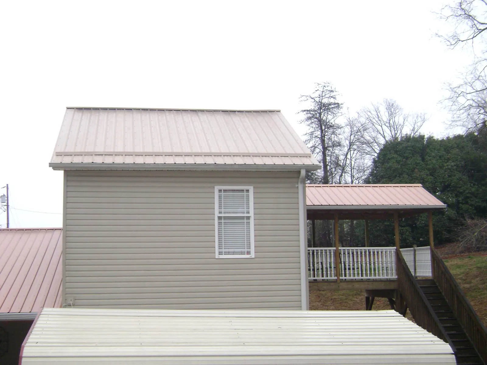Tan metal roofs on a two story addition and attached porch, from a Roof Replacement job in Wedgefield
