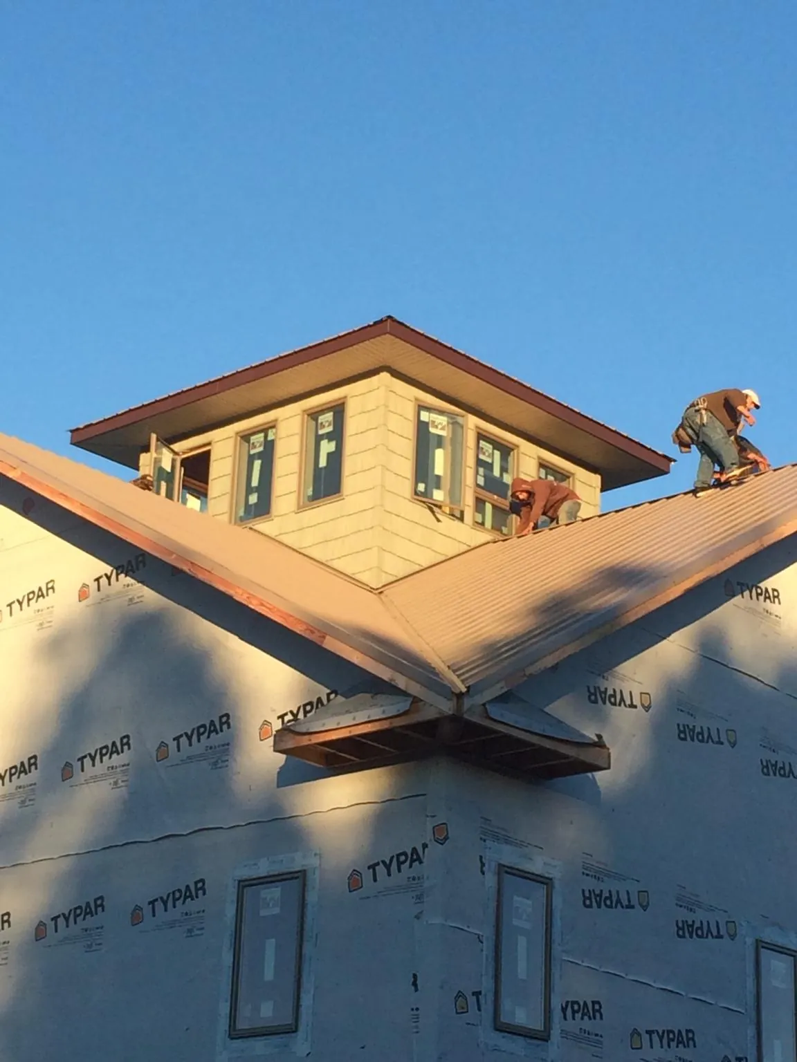 Roofers working around a rooftop cupola on a new metal roof at sunset — Roof Waterproofing in Wedgefield by Roofing Brothers